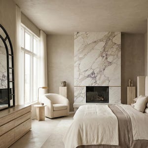 May include: A bedroom featuring a large arched floor mirror with a black frame, a light wood dresser, a cream-colored armchair, a marble fireplace, and a bed with neutral-toned bedding. The room has light-colored walls and large windows.