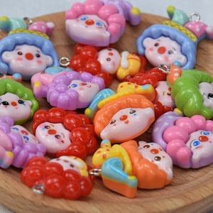 May include: A collection of colourful clown-themed charms with various facial expressions and hair styles. The charms are made of polymer clay and have a hole for attaching to jewellery or other crafts.