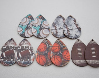 Könnte beinhalten: Ein Set mit 10 tropfenförmigen Ohrringen aus Holz mit verschiedenen Sportmotiven. Die Ohrringe zeigen Baseballs, Basketbälle und Fußbälle mit unterschiedlichen Mustern und Farben.