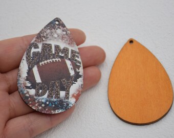 Könnte beinhalten: Zwei tropfenförmige Anhänger aus Holz. Ein Anhänger ist orange lackiert und der andere hat einen weißen Hintergrund mit einem Fußball, Leopardenmuster und den Worten "Game Day".