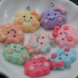 May include: Assortment of eight colorful cloud-shaped charms with happy faces, pink bows, and silver jump rings. Each charm has a different color and features a unique design.