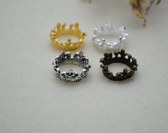 May include: Four small crown-shaped rings in gold, silver, and bronze.