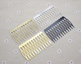 May include: Four metal hair combs in gold, silver, and black. Each comb has a series of evenly spaced teeth and a curved top. The combs are arranged on a beige fabric with a small white floral pattern.