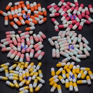 Puede incluir: Surtido de peque&ntilde;as c&aacute;psulas de pl&aacute;stico con caritas sonrientes. Las c&aacute;psulas son de varios colores, incluyendo naranja, rosa, azul claro y amarillo. Cada c&aacute;psula tiene una parte superior blanca y una parte inferior de color.