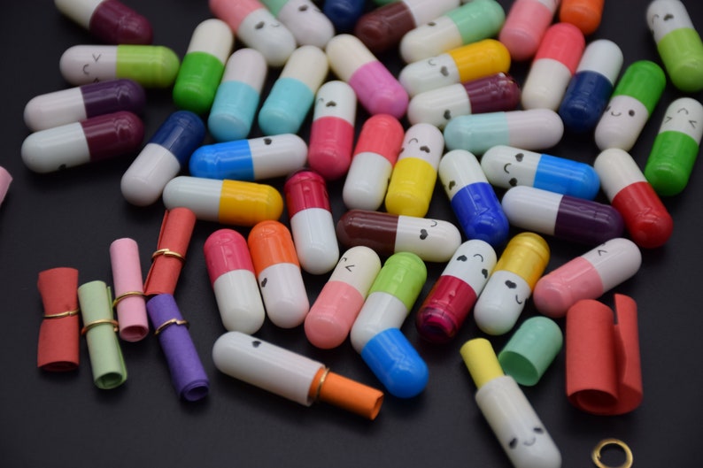 Puede incluir: Una colecci&oacute;n de c&aacute;psulas coloridas con caras felices en ellas. Las c&aacute;psulas est&aacute;n llenas de peque&ntilde;os trozos de papel enrollados.
