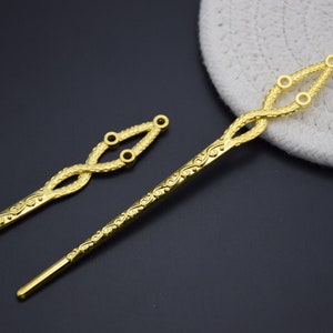 May include: Two gold hair sticks with intricate designs. The sticks are about 10 inches long and have a decorative, twisted design at the top. The sticks are perfect for adding a touch of elegance to any hairstyle.