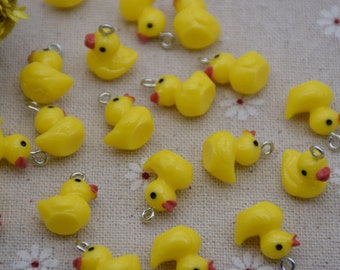 May include: A collection of yellow rubber duck charms with silver rings. The ducks are in various poses, some with their beaks open and some with their wings spread.