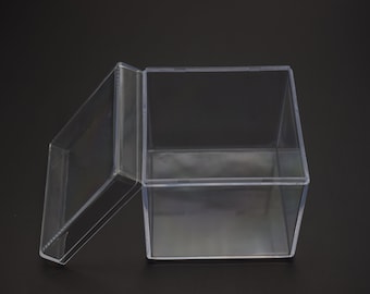 May include: A clear plastic box with a lid. The box is square and has a smooth surface. The lid is slightly ajar.