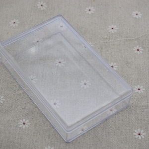 May include: A clear plastic storage box with a hinged lid. The box is empty and appears to be made of durable, lightweight plastic.
