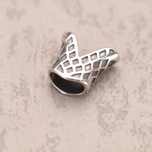 May include: A silver pendant with a geometric design. The pendant is shaped like a V and has a textured surface.
