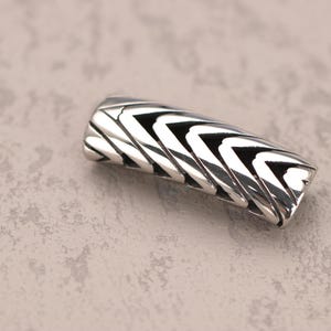 May include: A silver bracelet with a geometric pattern.