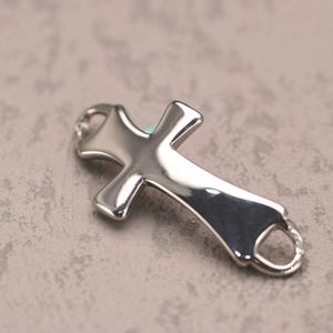 May include: A silver-toned cross charm with a smooth, polished finish. The cross has a simple, elegant design and is perfect for adding a touch of faith to jewelry.