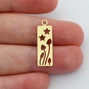 May include: Gold-toned metal charm with a rectangular shape and a cutout design of mushrooms and stars.