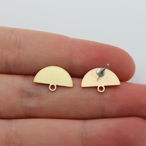 May include: Two gold-colored, half-circle stud earrings. Each earring has a small loop at the bottom and a post on the back for securing. The earrings are displayed on a light background.