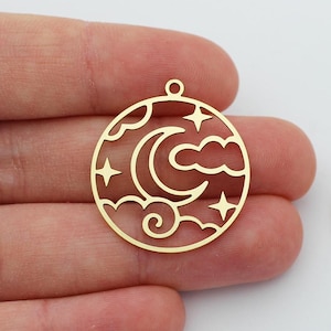 Könnte beinhalten: Goldener Metall-Anhänger mit ausgeschnittenem Halbmond, Wolken und Sternen. Der Anhänger ist rund und hat oben ein Loch zum Aufhängen.