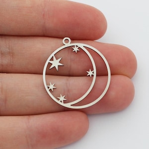 May include: Silver charm with a crescent moon and stars cut out. The charm has a hole at the top for attaching to a necklace or bracelet.