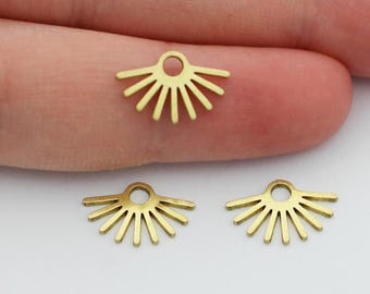 May include: Three small, gold-colored sunburst charms. Each charm has a circular loop at the top for attaching to jewelry. The sunburst design features a series of straight lines radiating outward from a central point.