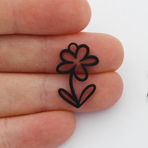 May include: Two black metal flower charms with a simple outline design. The charms are about the size of a fingernail.