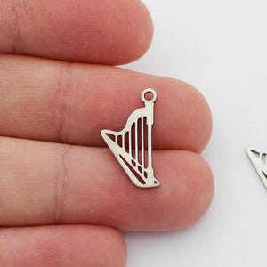 May include: Two silver harp charms with a hole at the top for attaching to jewelry or other crafts.