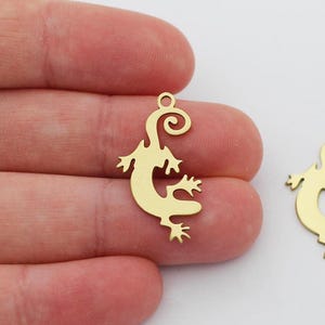 May include: Two gold-colored metal lizard charms with a curled tail. The charms are about 2 inches long and are perfect for jewelry making.