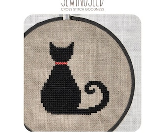 May include: A black cat cross stitch pattern with a red collar, in a round embroidery hoop. The pattern is on a beige linen fabric. The text "Instant Download Pattern" is below the hoop.