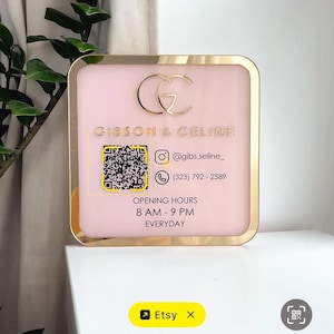 Può includere: Un cartello quadrato rosa con una cornice dorata presenta il testo "GIBSON & CELINE" e un codice QR. Il cartello include anche informazioni di contatto e orari di apertura: 8:00 - 21:00 tutti i giorni. Il logo Etsy si trova in basso a sinistra.