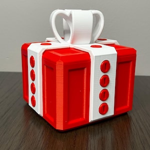 May include: A red and white gift box with a white bow on top. The box has a textured surface and is decorated with red circles.