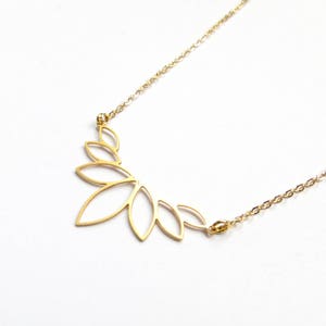 May include: A gold necklace featuring a delicate, leaf-shaped pendant. The pendant is crafted from thin metal and has a delicate, openwork design.