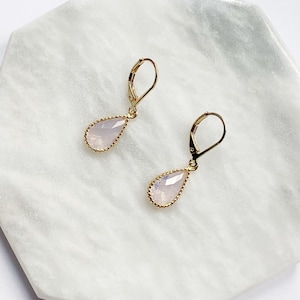 May include: A pair of gold earrings with a teardrop-shaped pink stone.