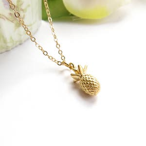 May include: A gold chain necklace with a pineapple pendant. The pineapple is detailed with a textured surface and a small stem.
