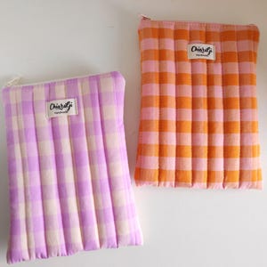 Può includere: Due pochette trapuntate con cerniera e motivo a quadretti. Una è lavanda e crema, l'altra arancione e rosa. Ogni pochette ha una piccola etichetta bianca con la scritta "Chiaralji Handmade".