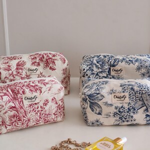 Puede incluir: Cuatro neceseres con estampados florales. Dos bolsas presentan un diseño floral rojo y dos tienen un diseño floral azul. Cada bolsa tiene cierre de cremallera y una pequeña etiqueta que dice "Chiaralgi handmade".