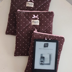 Könnte beinhalten: Drei braune, gesteppte Taschen mit weißen Punkten, rosa Reißverschlüssen und kleinen rosa Schleifen. Jede Tasche hat ein rechteckiges Etikett mit der Aufschrift ChiaraGi Handmade. Ein schwarzer E-Reader liegt auf der vordersten Tasche.