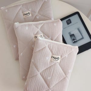 Può includere: Tre pochette trapuntate color beige con un motivo a cuori bianchi e chiusura a zip bianca. Ogni pochette presenta un'etichetta rettangolare in tessuto con la scritta ChiaraGi Handmade. Realizzate in tessuto morbido con cuciture a rombi.