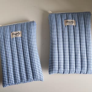 Puede incluir: Dos estuches acolchados de cuadros azules y blancos con cierres de cremallera. Cada estuche tiene una pequeña etiqueta rectangular que dice "ChiaraGi Handmade". Los estuches tienen forma rectangular vertical.