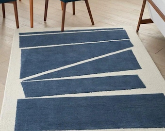 May include: A blue and white geometric area rug with a modern design. The rug has a white border and a series of blue stripes and triangles.