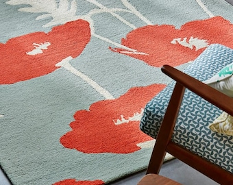 May include: A blue and orange area rug with a floral pattern. The rug features large, stylized poppy flowers with white stems and leaves.