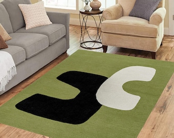 May include: A green rug with a black and white abstract design. The design features two large, curved shapes that resemble the letter "U".