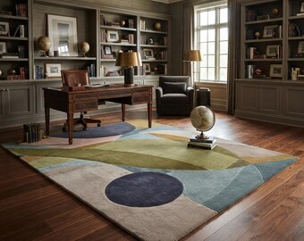May include: A large rectangular area rug featuring an abstract pattern of overlapping geometric shapes in shades of olive green, slate blue, beige, and tan. The design includes a prominent dark blue circle and curved color-blocked sections.