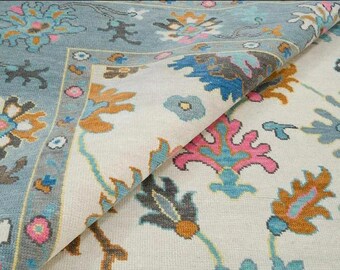 May include: A close-up of a patterned rug with a light blue and white background. The rug features a floral design with shades of blue, pink, and brown.