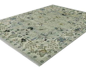 May include: A light gray rug with a floral pattern in shades of blue, brown, and black. The rug has a border with a geometric design.