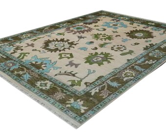 May include: A vintage rug with a cream background and a green and blue floral pattern. The rug has a border with a repeating pattern of flowers and leaves.