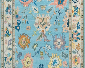 May include: A blue rug with a floral pattern in shades of pink, yellow, and green. The rug has a white border with a repeating pattern.