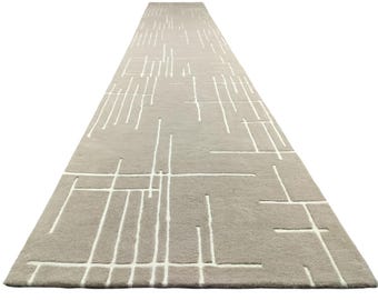 May include: A long, rectangular beige rug with a white geometric pattern of lines and squares.