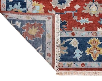May include: Close-up of the corner of a red, blue, and cream patterned rug with fringe. The rug has a floral design.