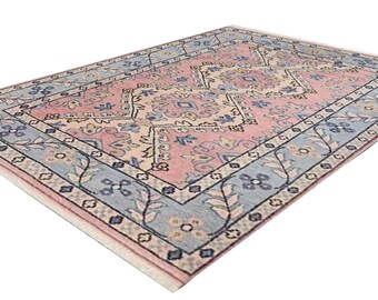 May include: A pink and blue patterned rug with a floral design. The rug has a light blue border with a darker blue and white geometric pattern.