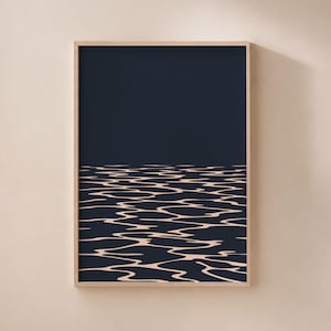 Puede incluir: Una impresión de arte mural rectangular en un marco de madera clara con un fondo azul marino oscuro. La parte inferior de la impresión muestra una representación gráfica estilizada de agua ondulante con líneas horizontales beige claro.