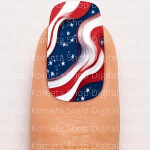 May include: A nail with a patriotic design featuring red and white stripes, blue background with white stars, and a wavy pattern. The nail art is on a finger, with the text "Digital Kometa Shop Digital Komet" in the background.