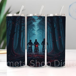 May include: A tall, cylindrical tumbler with a lid and straw. The tumbler features a dark forest scene with three figures on bicycles. The design is predominantly dark blue and red, with the text "meta Shop Digital" at the bottom.