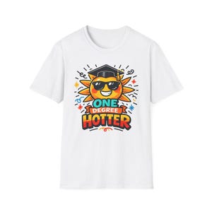 Könnte beinhalten: Weißes T-Shirt mit einer Cartoon-Sonne, die eine Sonnenbrille und einen Abschluss-Hut trägt. Die Sonne hat den Text "ONE DEGREE HOTTER" in bunten Buchstaben. Das Design umfasst Sterne und dekorative Linien.